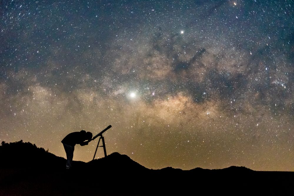 A person observing the night sky through one of the best telescopes